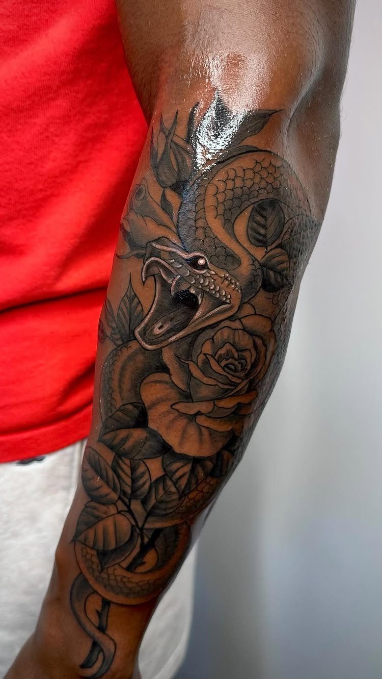 Snake and rose tattoo on a person's dark skin toned forearm