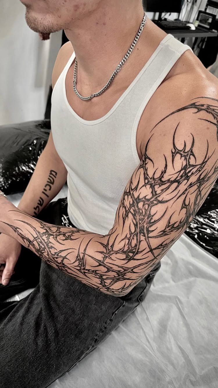 Tribal half sleeve tattoo with sharp black lines on a man's arm