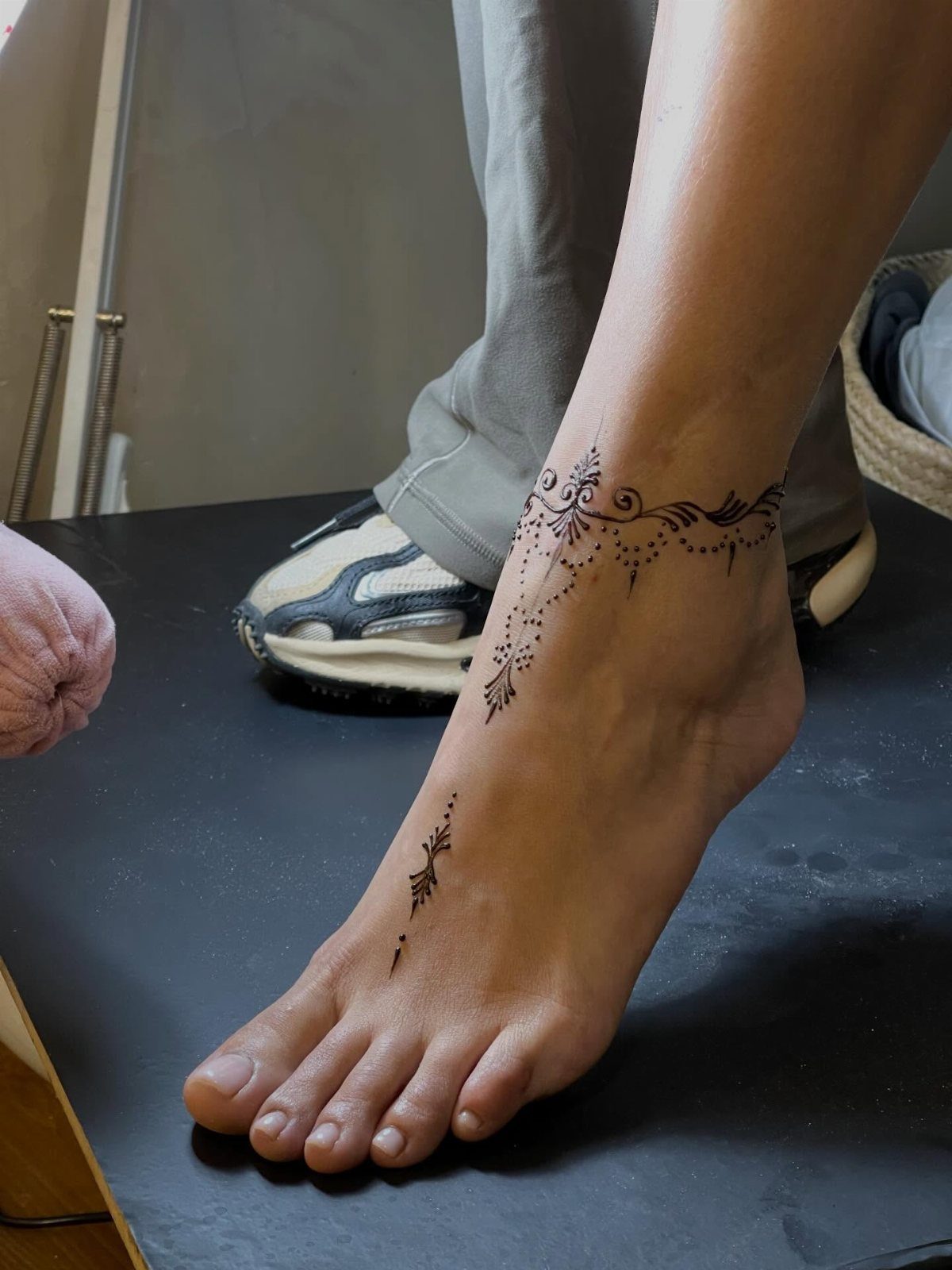 Foot and ankle with dark brown henna tattoos on a black background