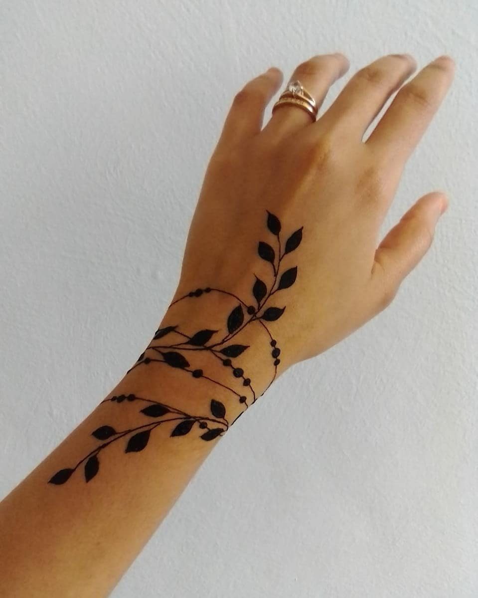 Henna tattoo of leafy vines wrapping around a wrist like a bangle bracelet.