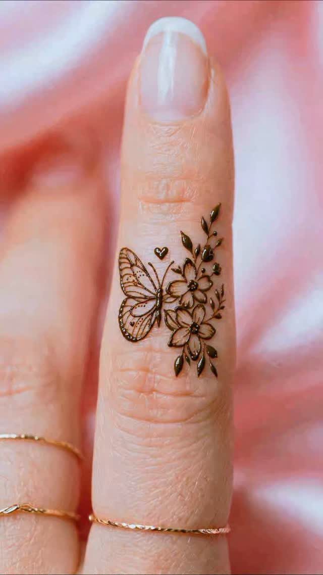 Henna tattoo of a butterfly and flowers on a person's finger.