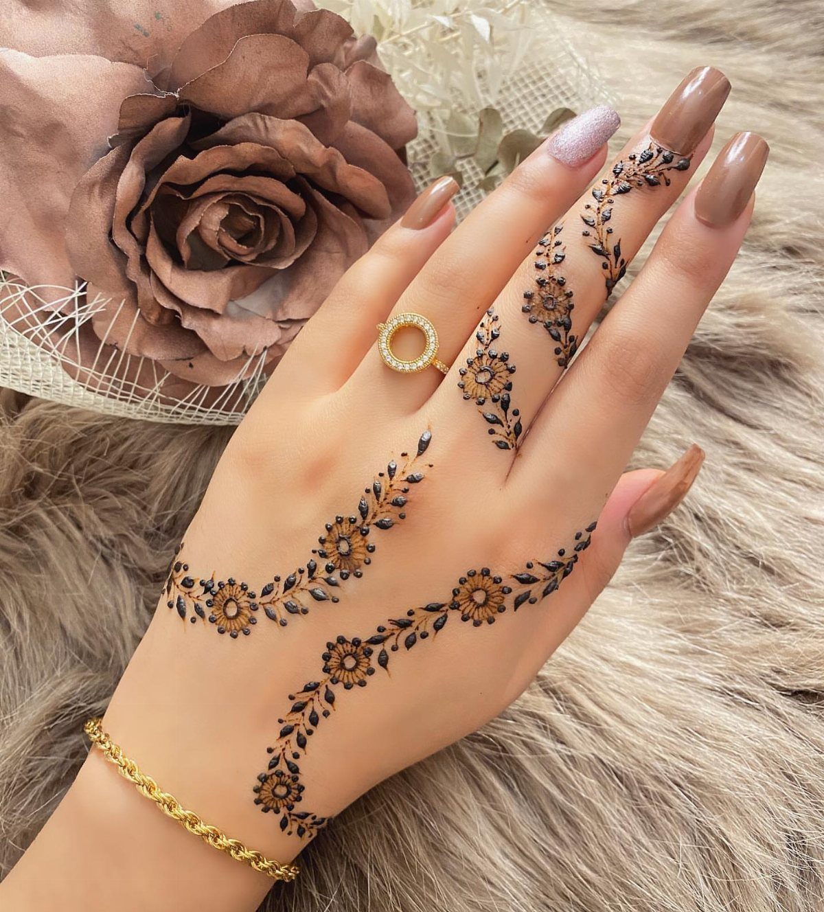 Hand with brown henna floral chain tattoos and vines on a furry background