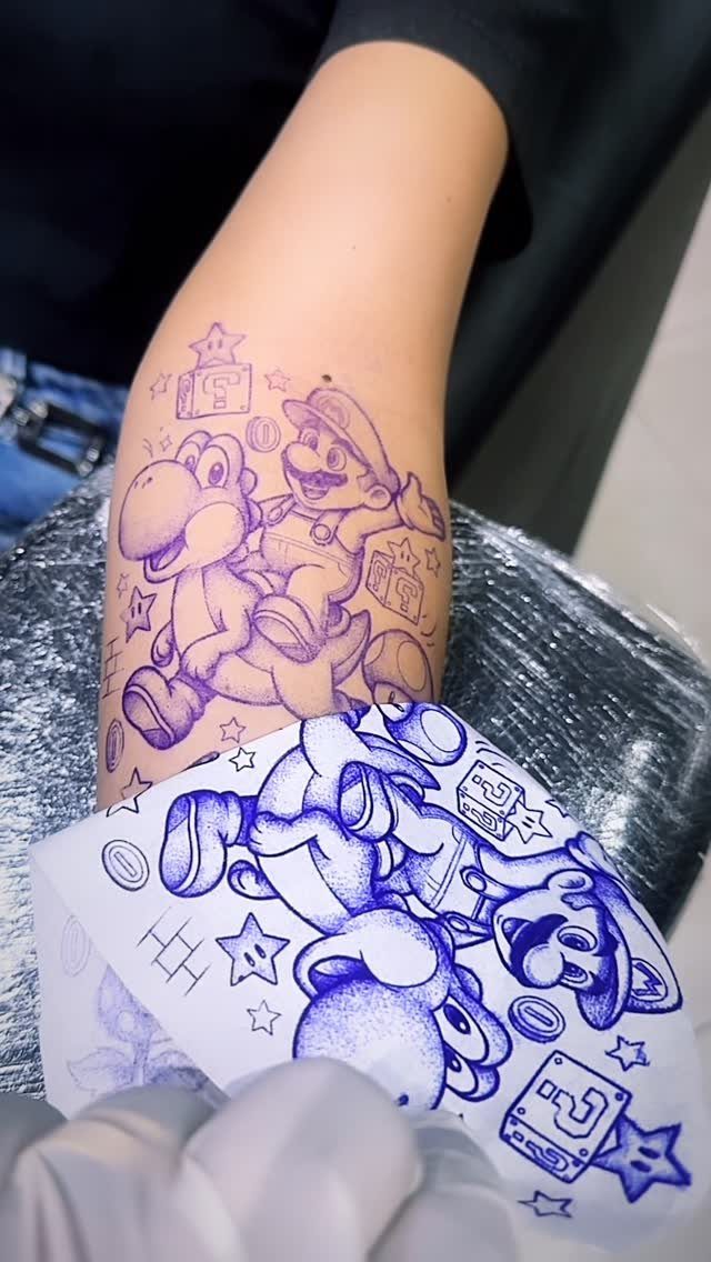 Mario and Yoshi tattoo stencil applied to a forearm with transfer paper