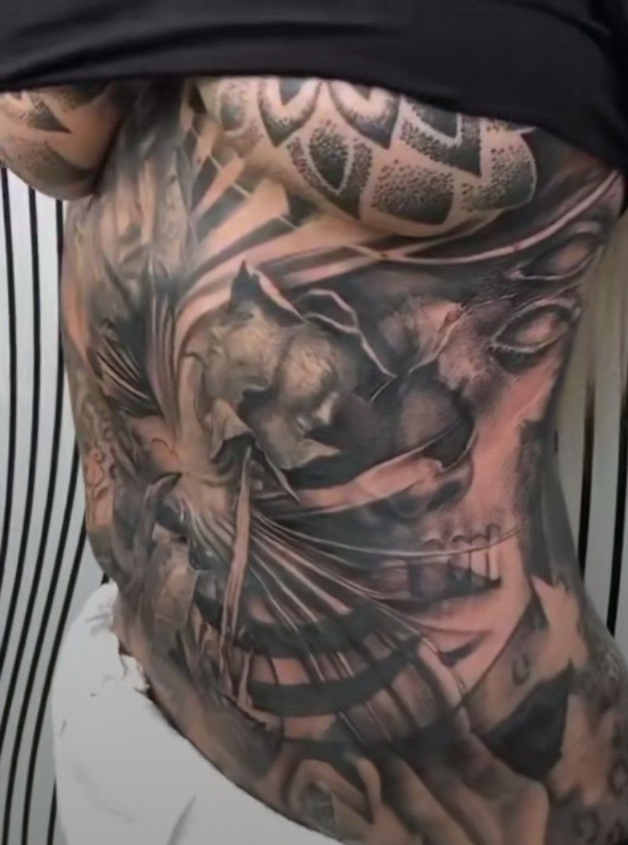 Detailed black and grey skull tattoo covering a person's stomach and torso area.