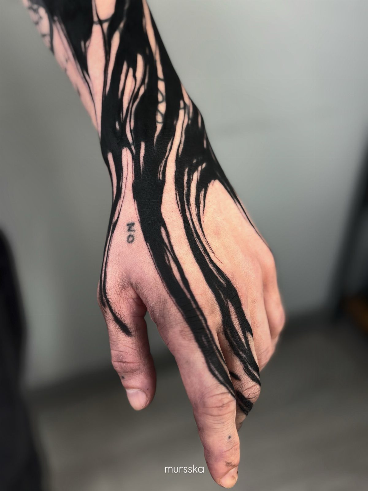 Hand and wrist with bold black flowing ink tattoos and the word NO