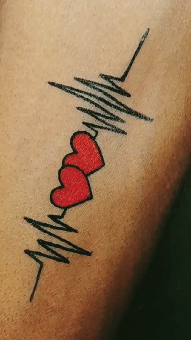 Two red hearts between black heartbeat pulse lines tattooed on skin.