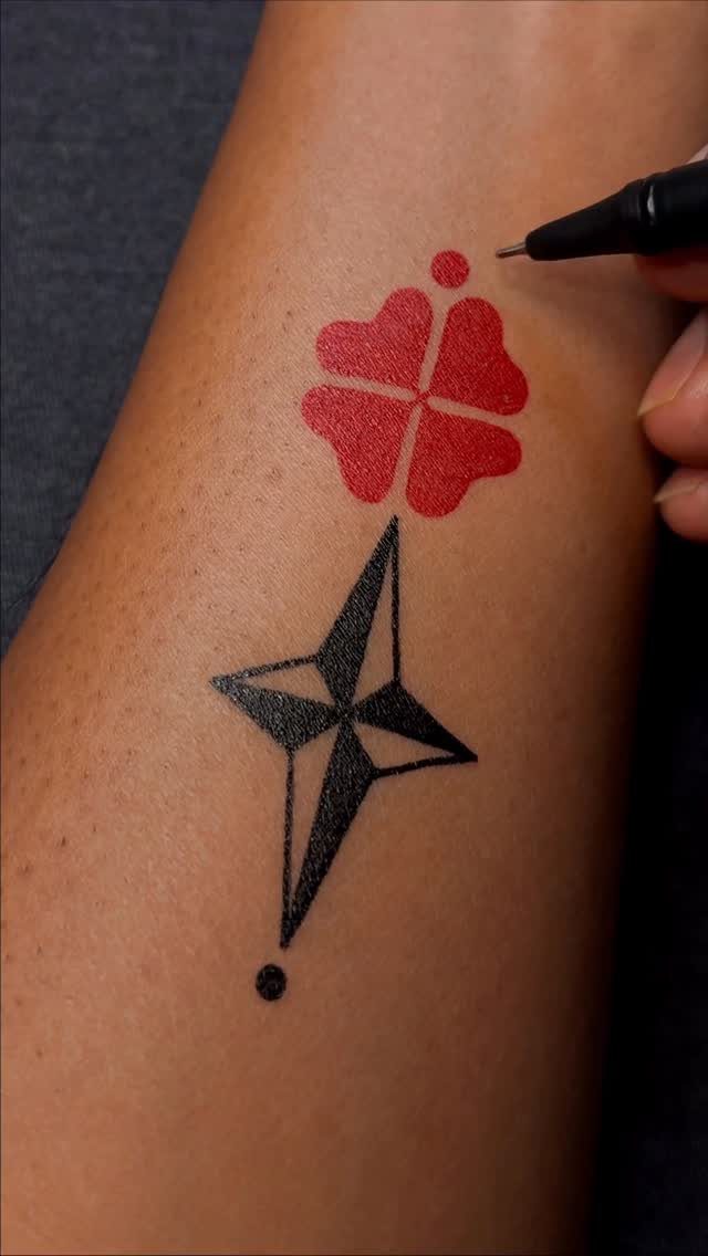 Red clover and black geometric star symbols drawn on a person's arm with pen