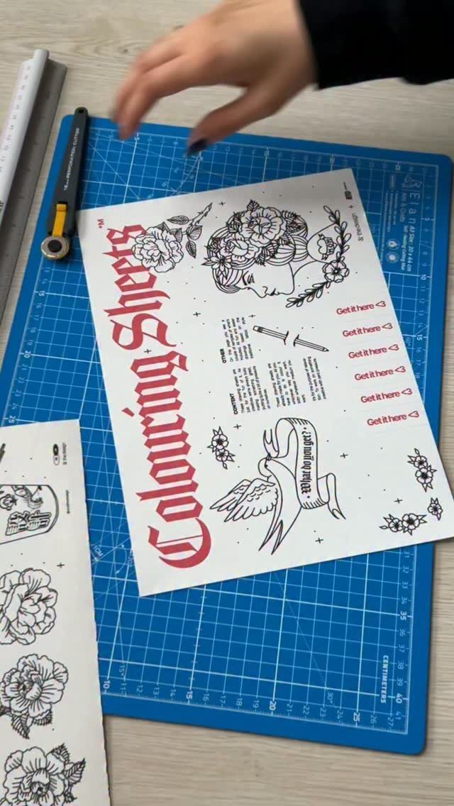 Tattoo style coloring pages on a blue cutting mat with a utility knife.