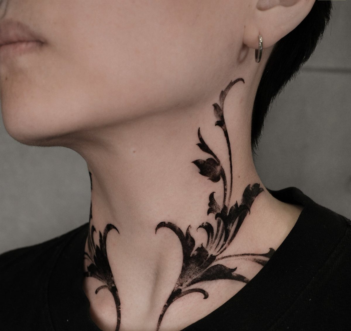Botanical vine tattoo with black ink leaves wrapping around a person's neck.