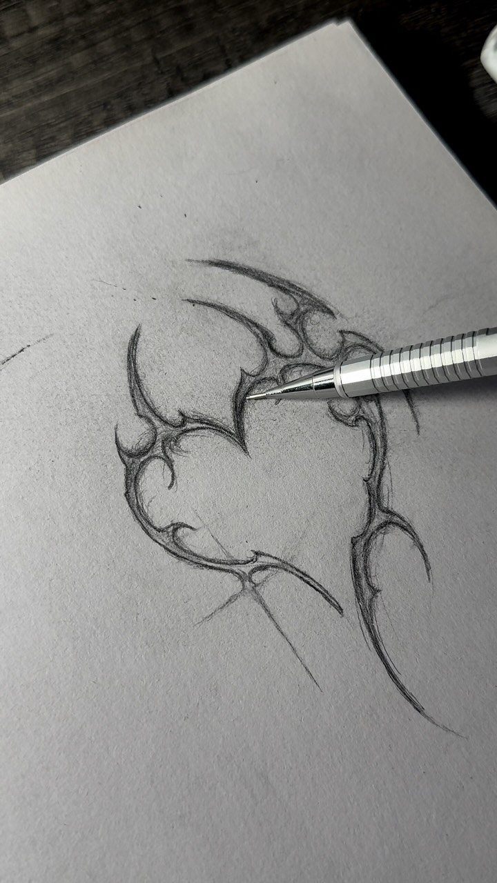Mechanical pencil sketching a tribal tattoo design on white drawing paper.