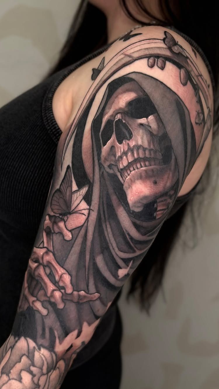 Grim Reaper skull tattoo with a hood and butterflies on an arm