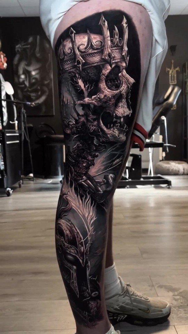 Skull wearing a crown tattoo on a person's leg with detailed gothic shading