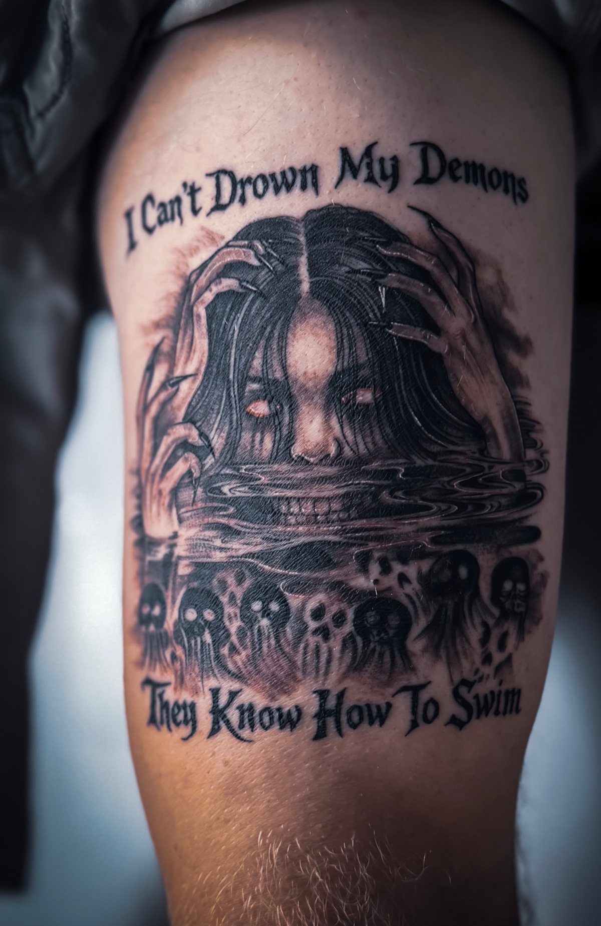 Tattoo on a thigh showing a demonic woman emerging from water with skulls.
