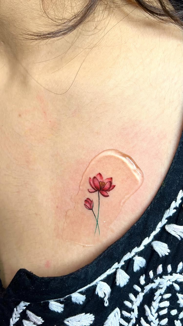 Pink lotus flower tattoo on a person's chest covered by a clear bandage.