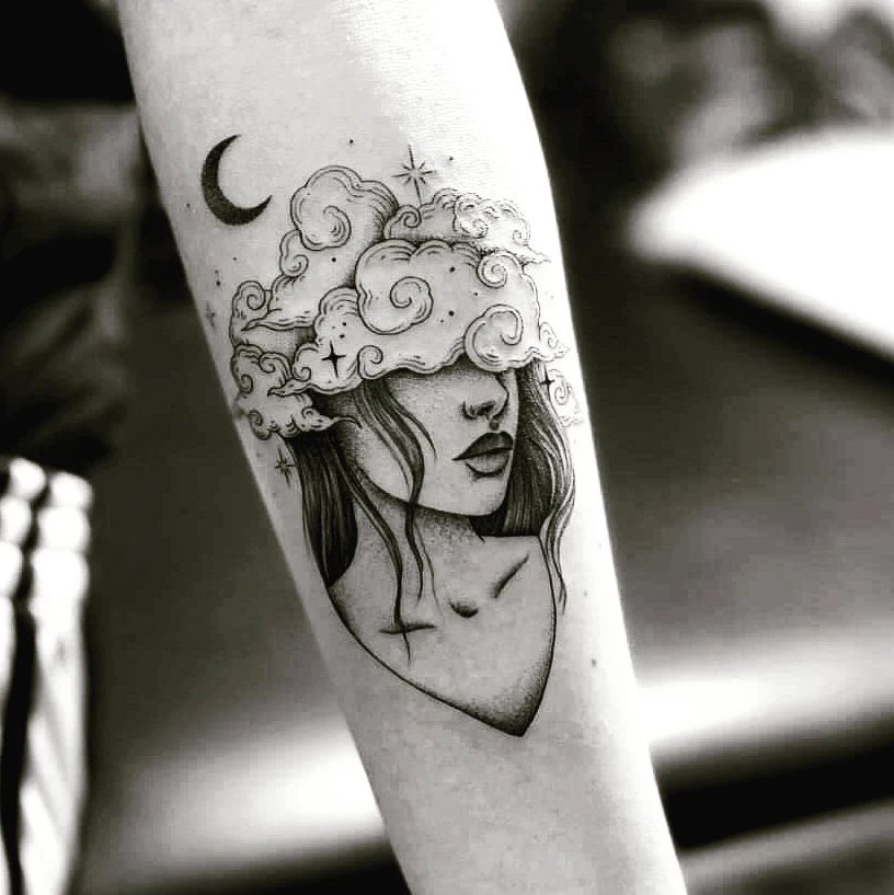Tattoo of a woman's face with clouds over her eyes and a crescent moon.