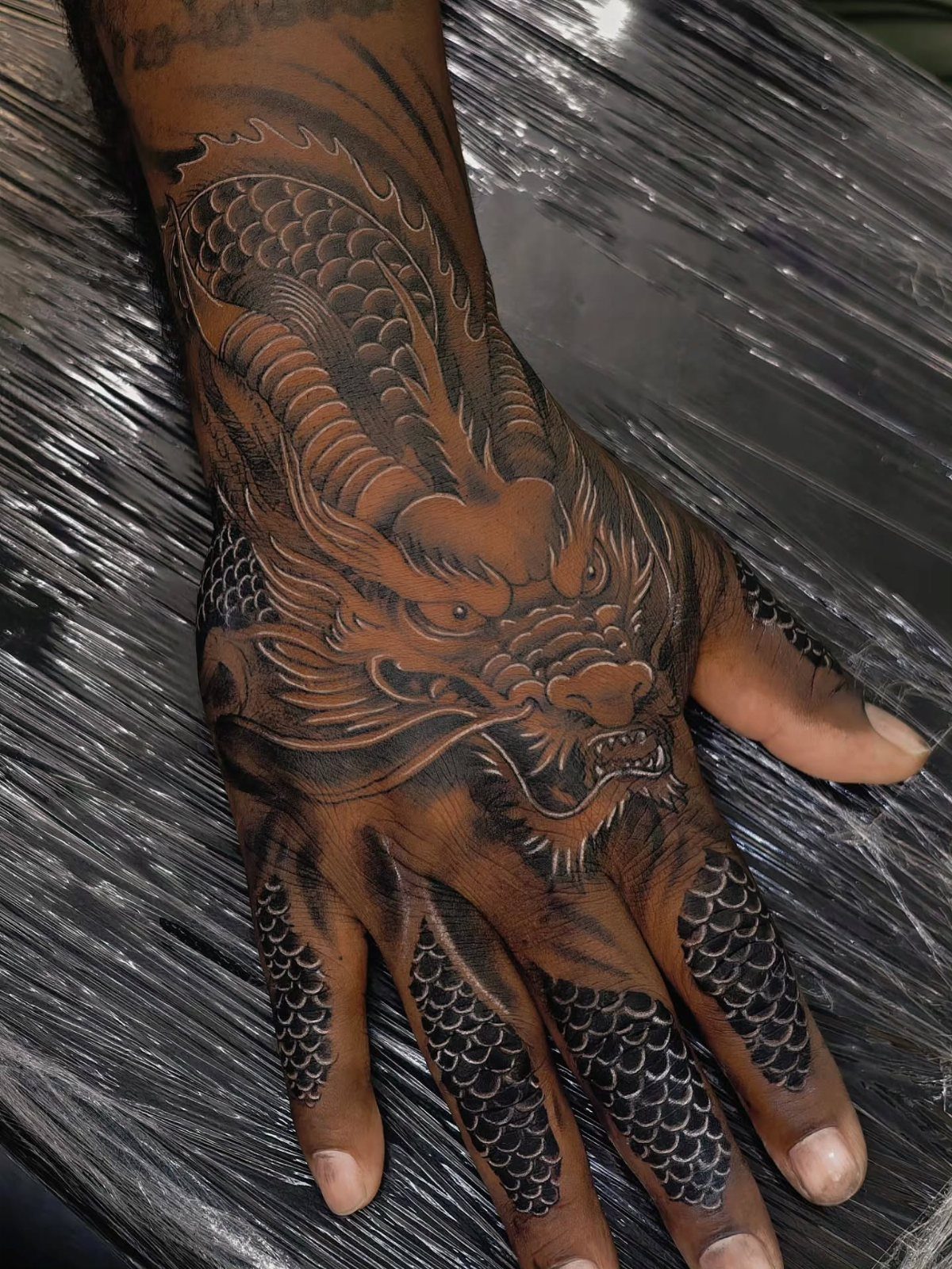 Dragon tattoo on the hand and wrist of a person with dark skin