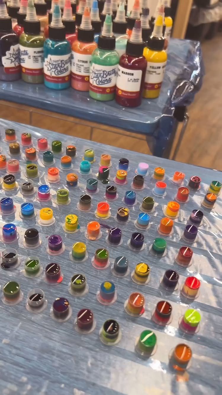 Colorful tattoo ink bottles and small ink caps arranged on a plastic table.