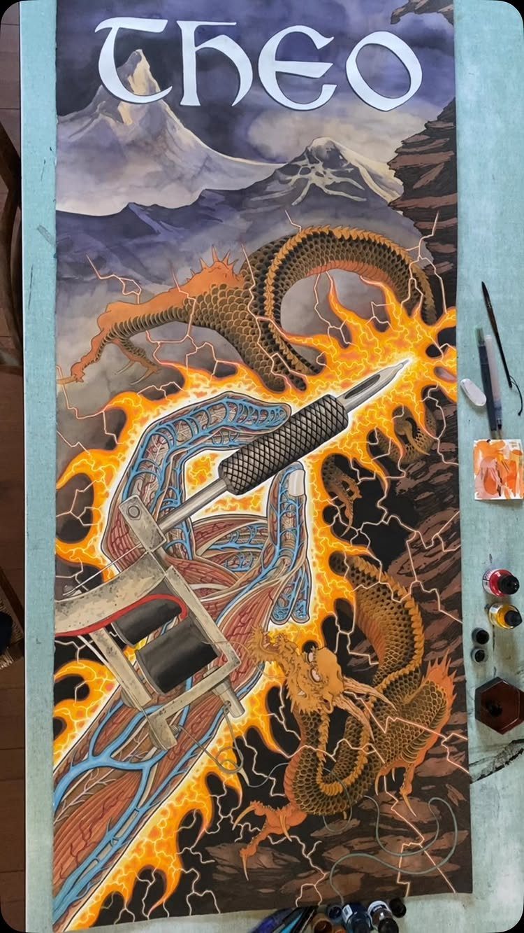 Hand holding a tattoo machine surrounded by flames and a golden dragon drawing.