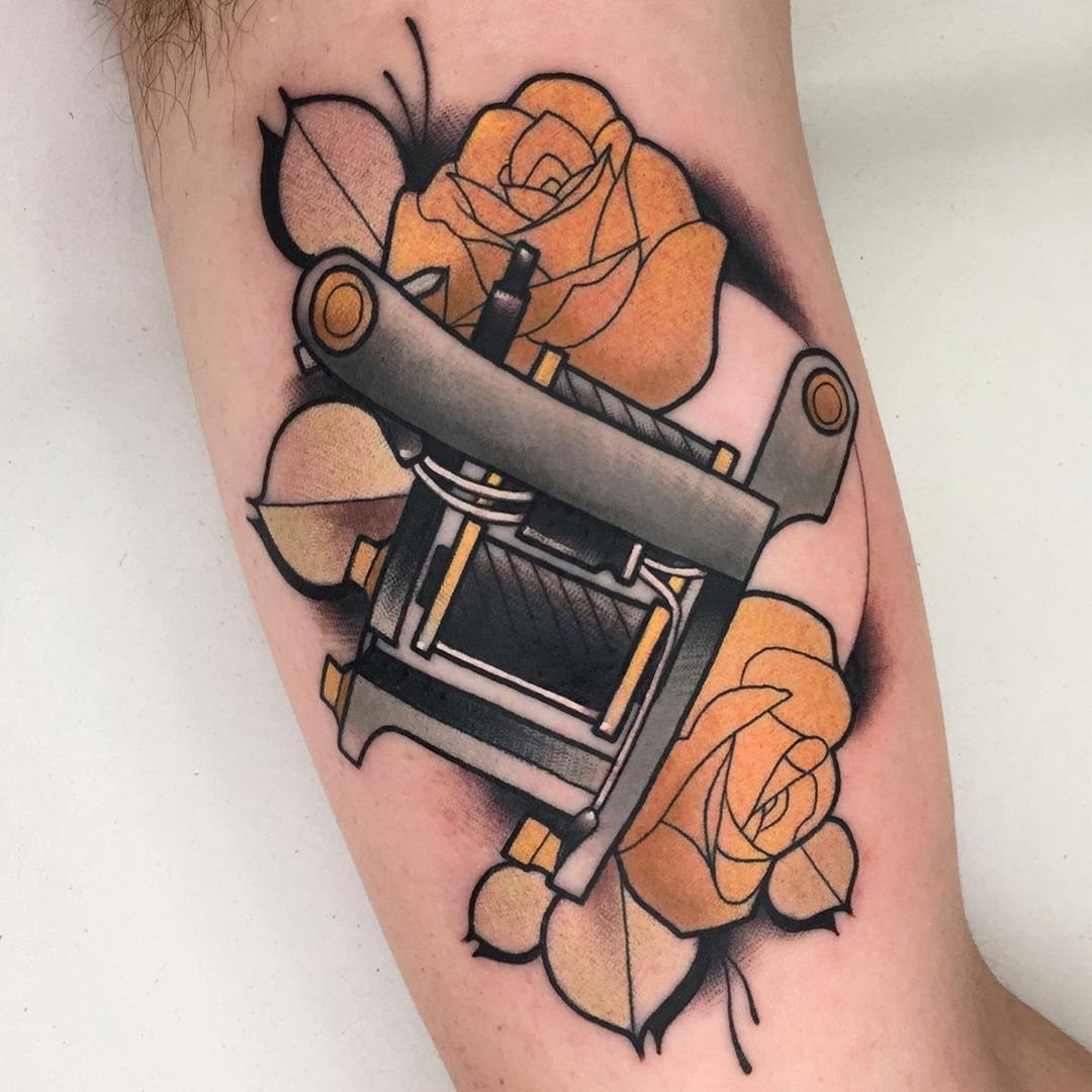 Tattoo machine surrounded by yellow roses and leaves on a person's arm.