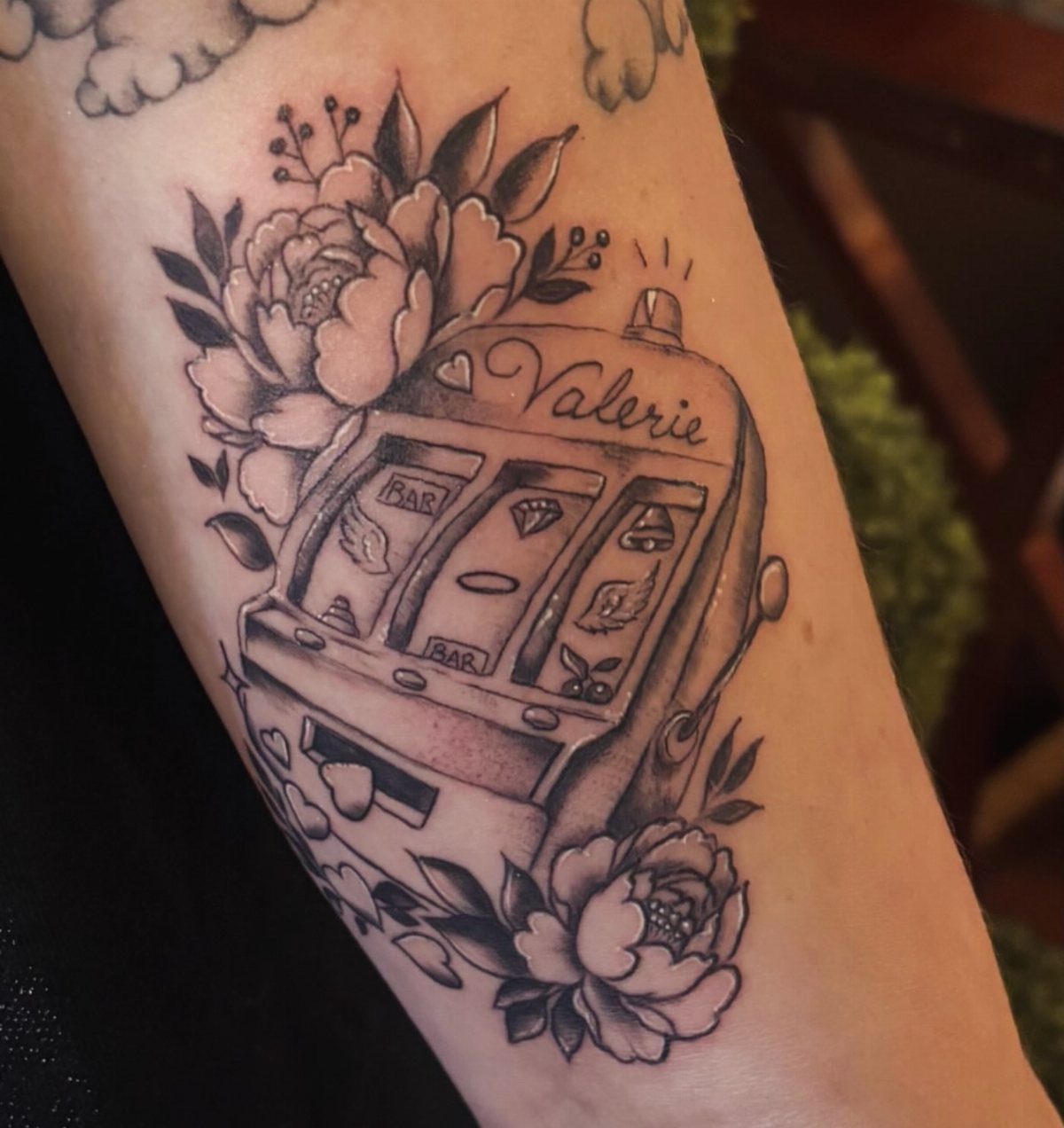 Black and grey slot machine tattoo with peonies and the name Valerie.