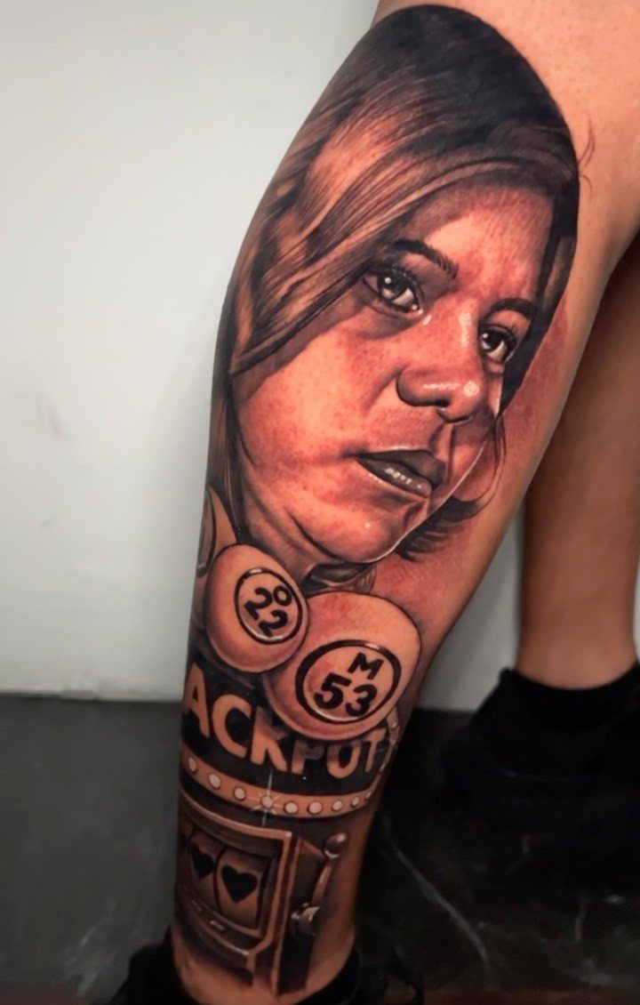 Tattoo of a woman's portrait above a slot machine and poker chips on a leg.