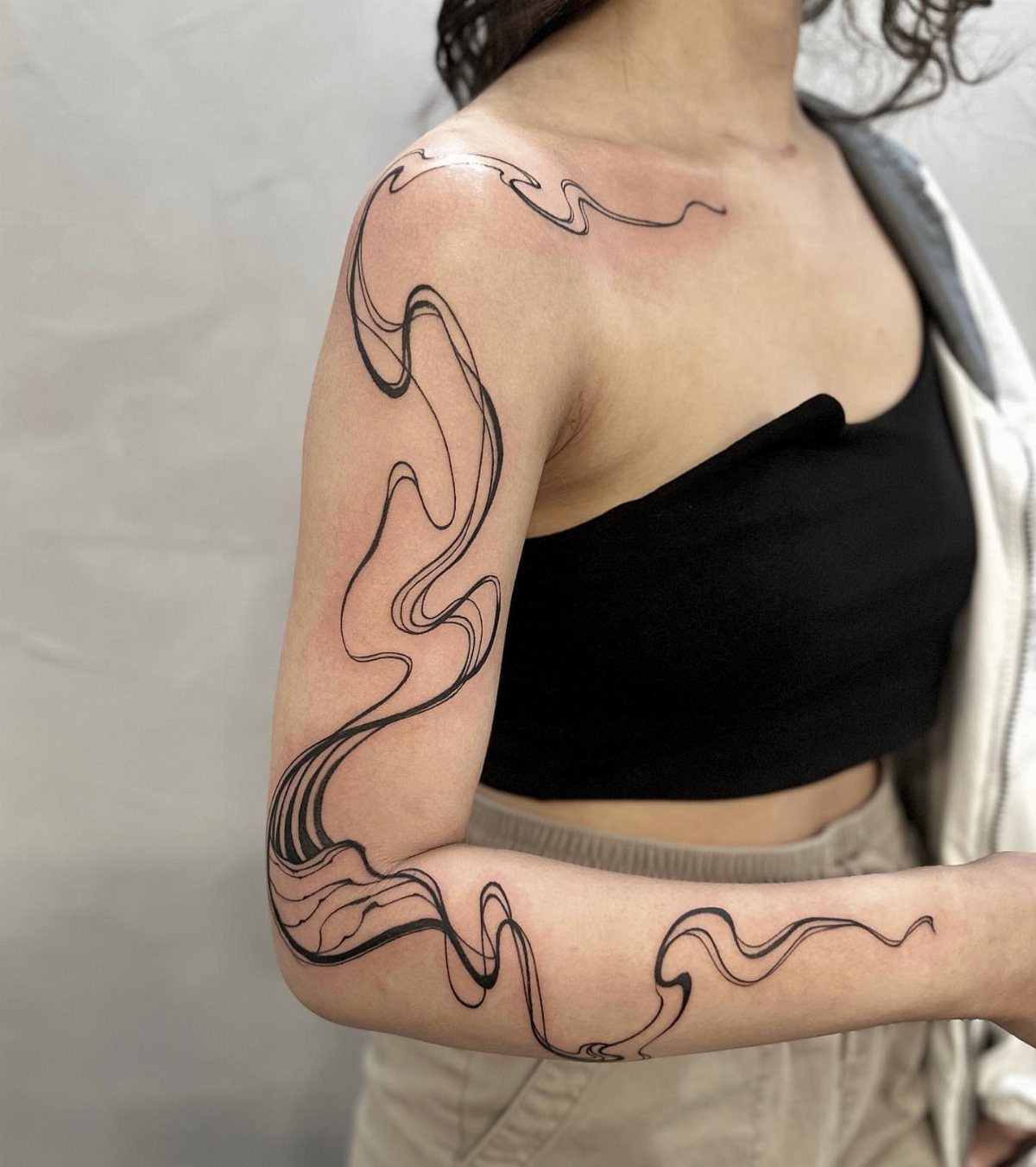 Abstract flowing line tattoo stencil on a person's shoulder and arm