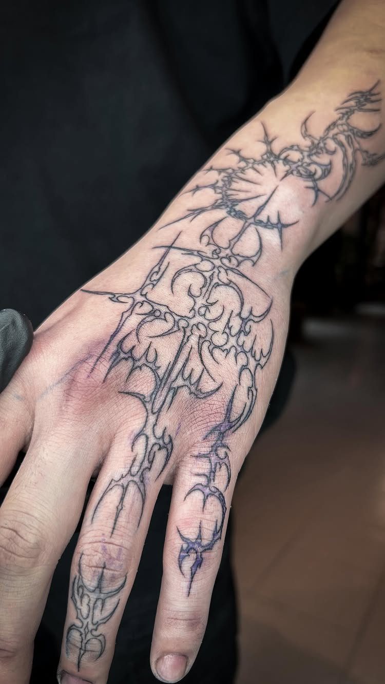 Tattoo stencil with intricate gothic patterns applied to a person's hand and forearm.