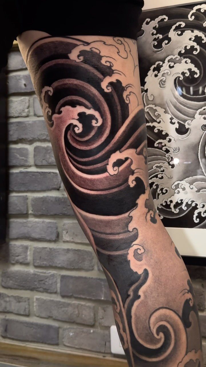 Japanese wave tattoo on a forearm with matching artwork in the background