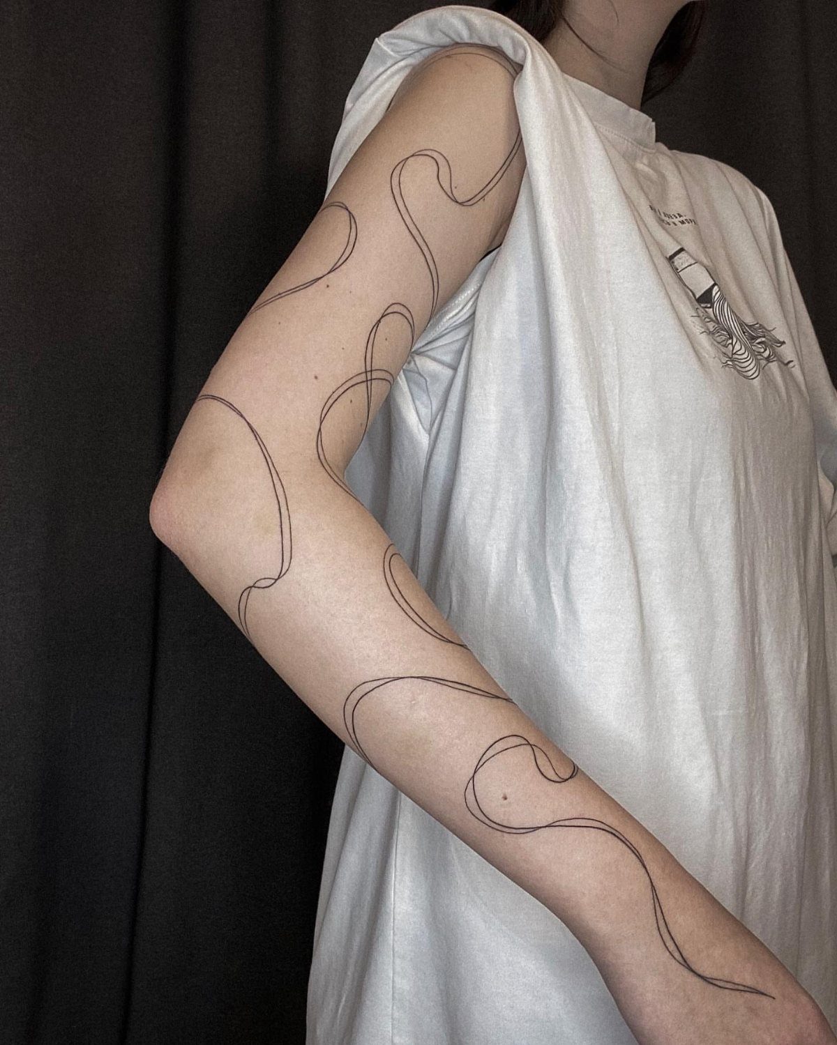 Tattoo stencil of a winding black line applied to a person's arm.