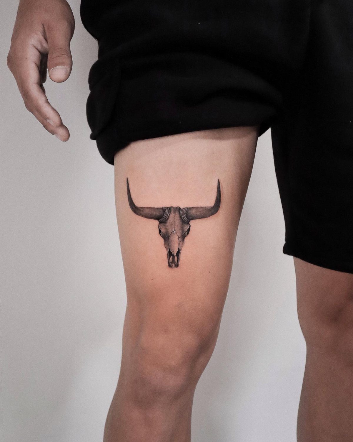 Bull skull tattoo with long horns on a person's thigh
