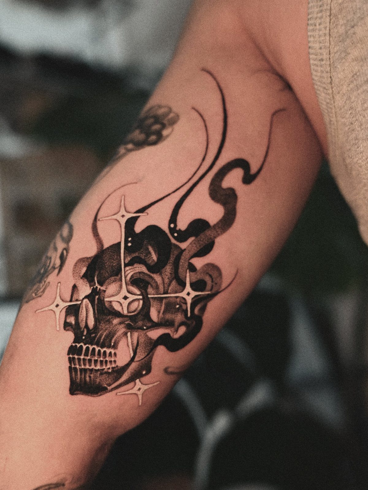 Skull tattoo with swirling flames and stars on a person's forearm