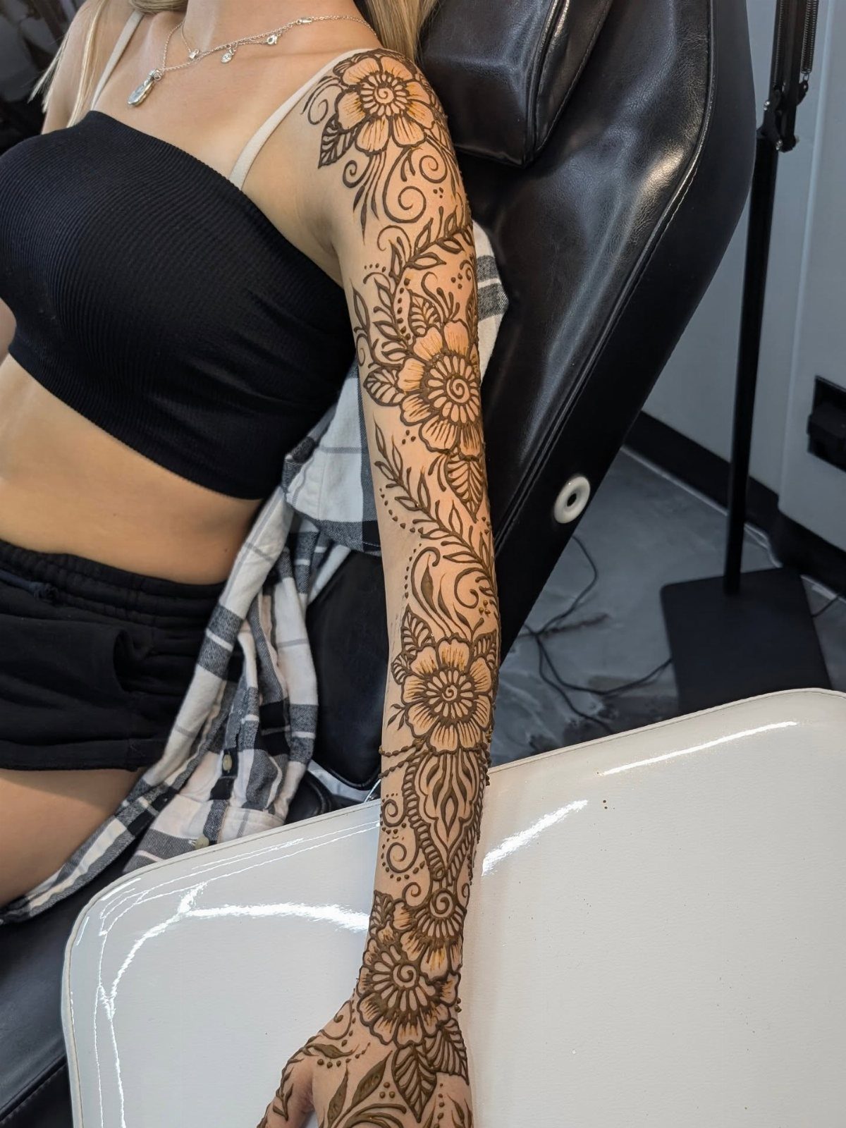 Brown floral henna-style tattoo covering a person's entire arm and hand.