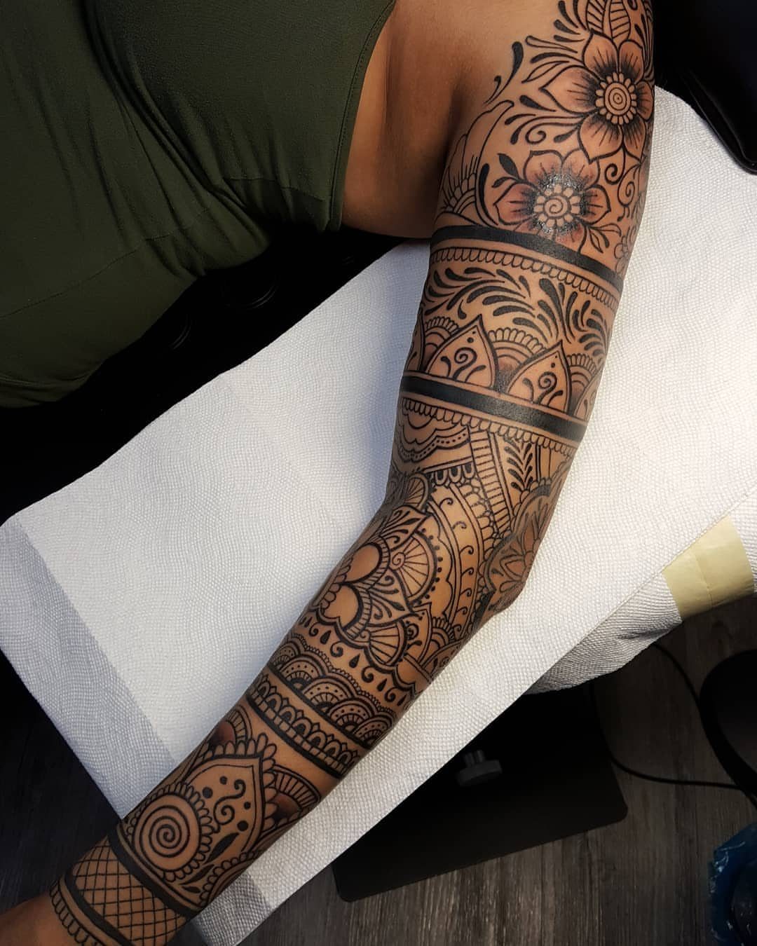 Intricate henna-style tattoo with floral and mandala patterns covering a person's arm and shoulder.