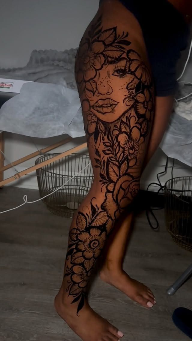 Leg with a black henna-style tattoo featuring floral patterns and a woman's face.