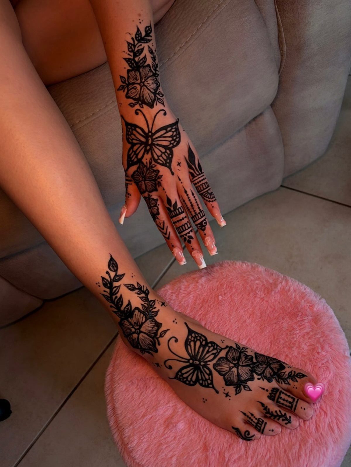 Intricate black ink tattoos with floral and butterfly designs on a hand and foot.