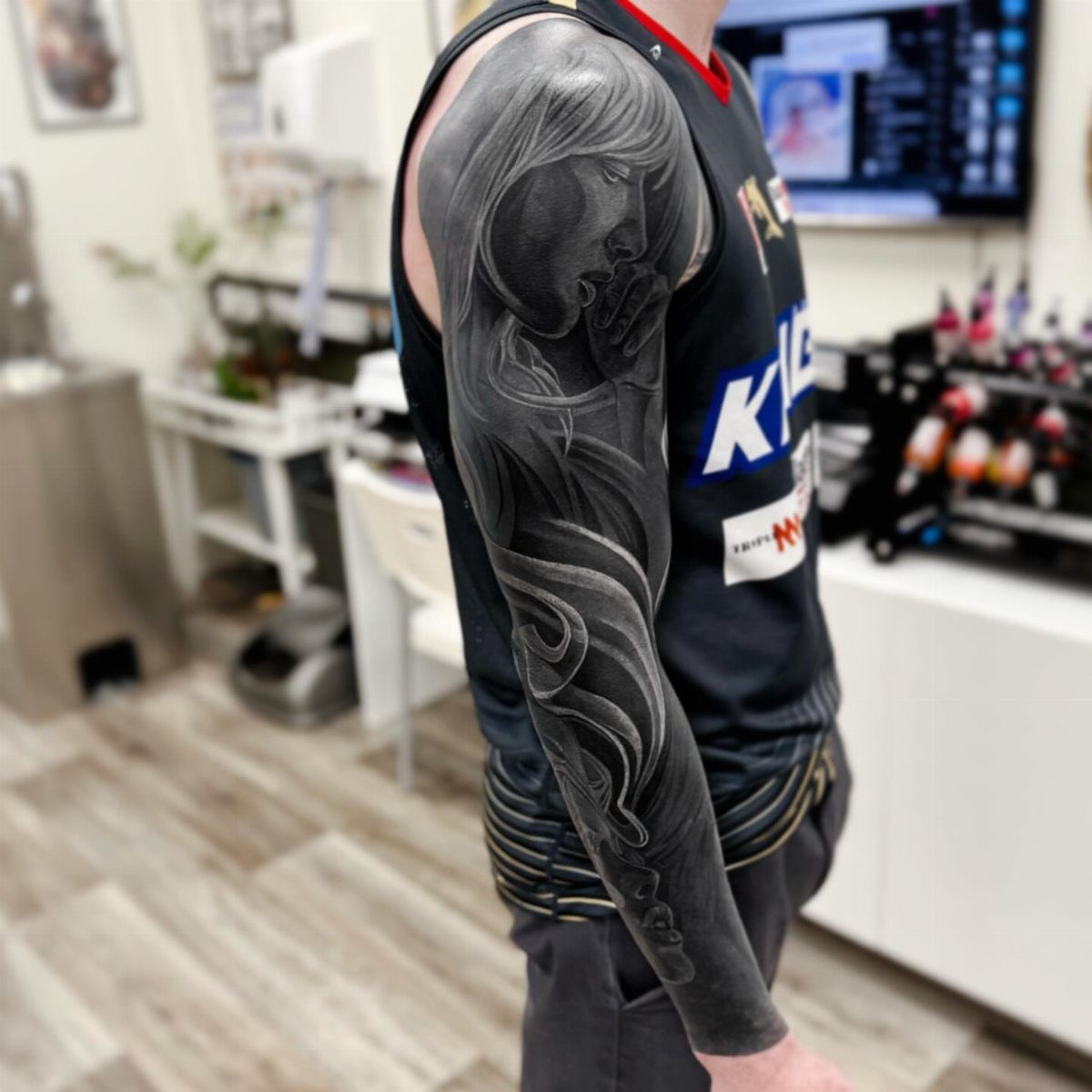 Detailed black and grey sleeve tattoo with bright white ink highlights on an arm