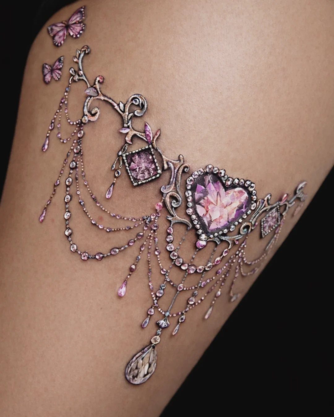 Ornate jewelry tattoo with pink gemstones and silver chains on dark skin.