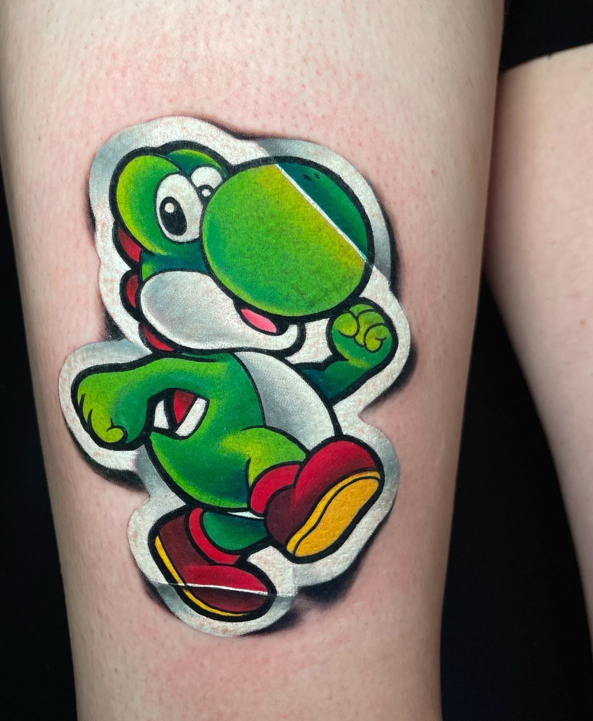 Yoshi tattoo with a white border and drop shadow resembling a sticker