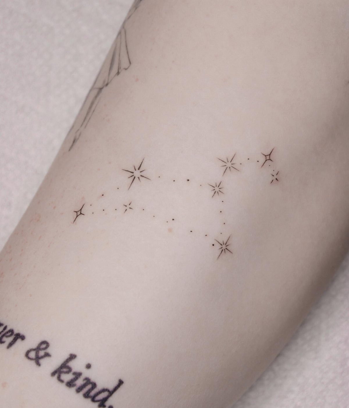 Constellation tattoo with small stars and dots on a person's pale skin.