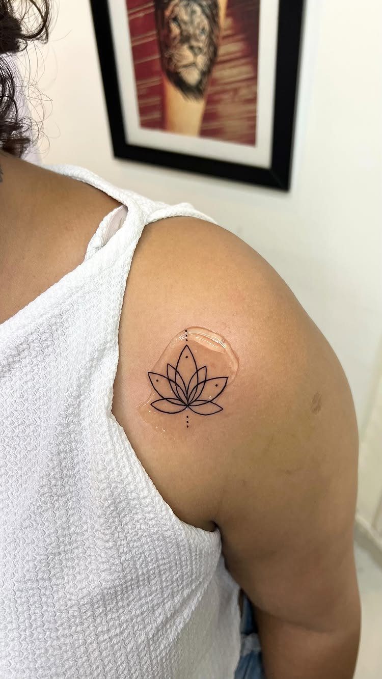Lotus flower tattoo on a person's shoulder with a small clear bandage
