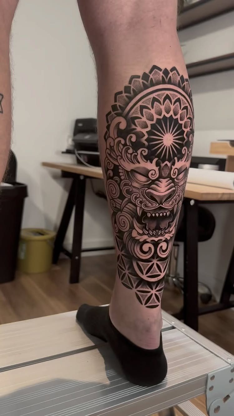 Tiger face tattoo with mandala and geometric patterns on a lower leg