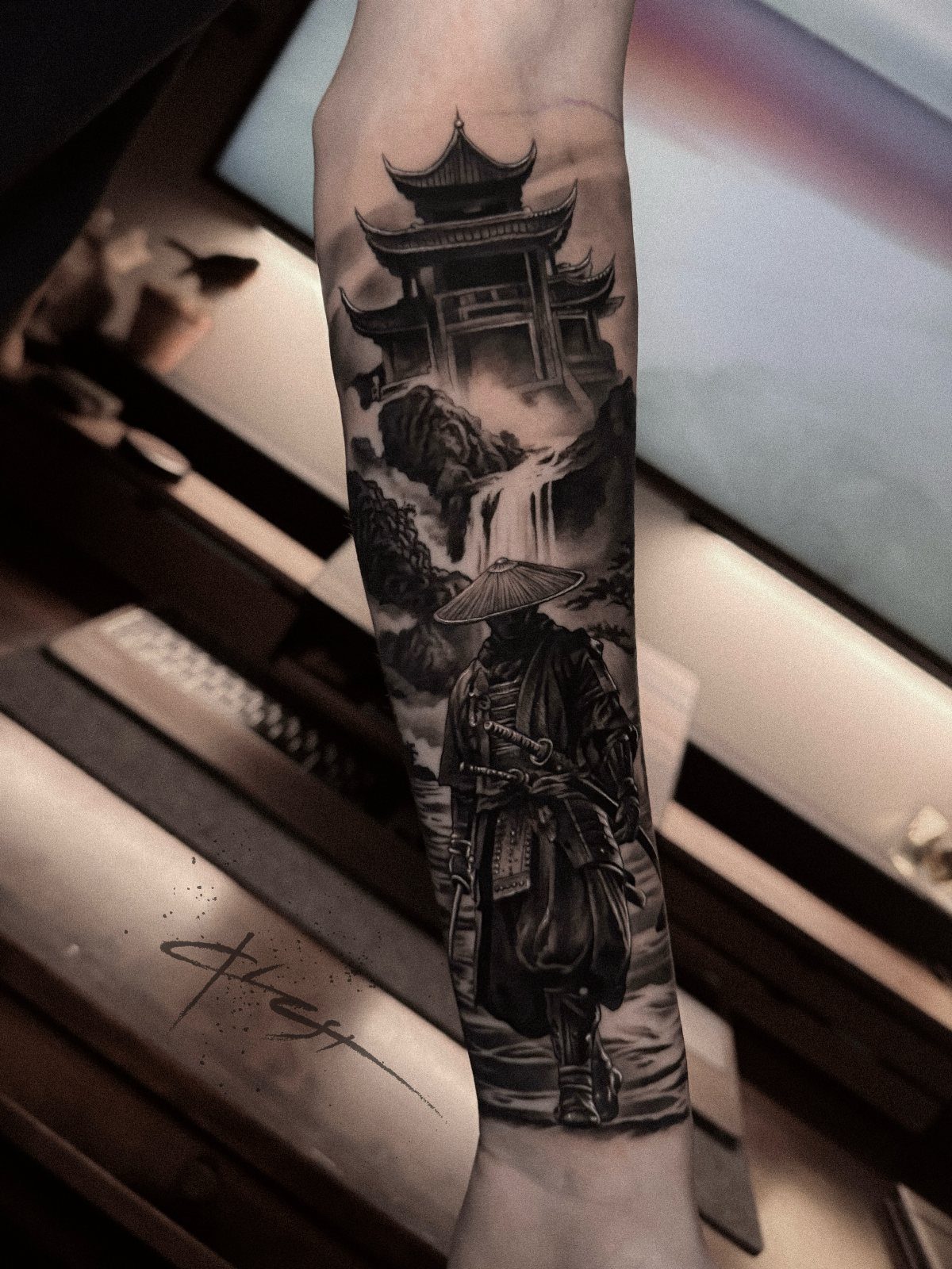 Samurai warrior tattoo on a forearm with a pagoda and waterfall background.