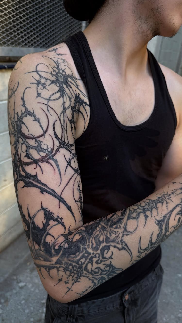 Full sleeve blackwork tattoo with abstract sharp patterns on a person's arm.