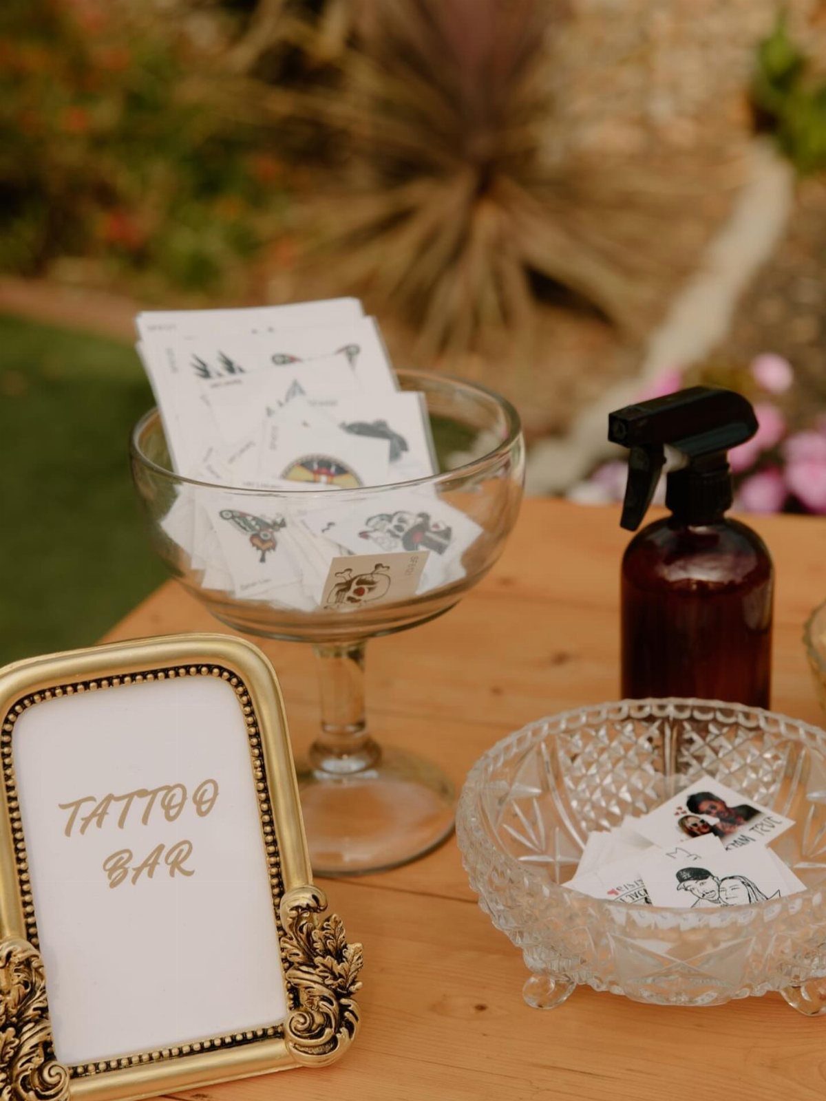 Tattoo bar setup with temporary tattoos in glass bowls and a gold sign.