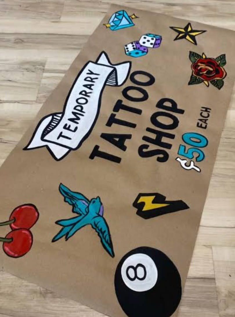 Brown paper sign for a temporary tattoo shop with colorful tattoo illustrations.