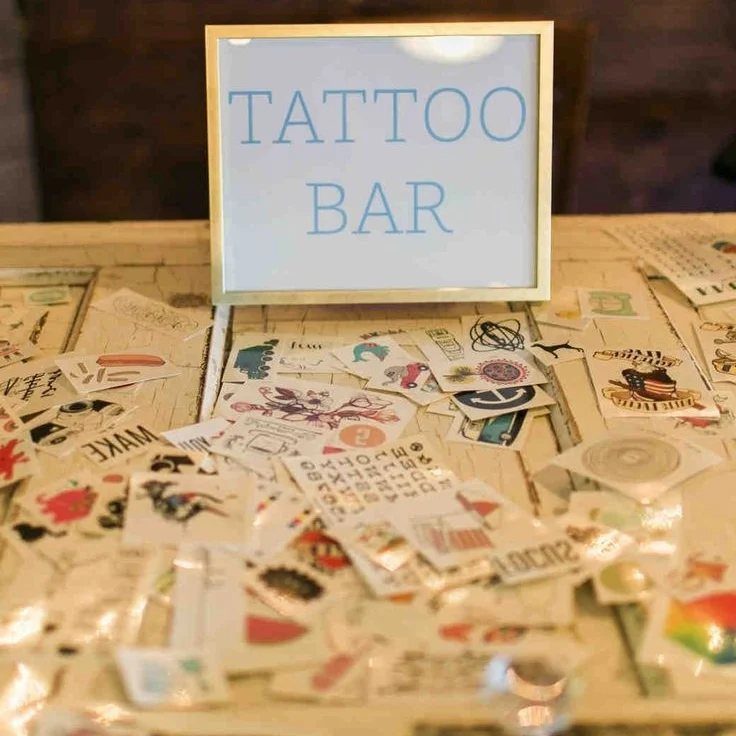Temporary tattoo sheets scattered on a table with a Tattoo Bar sign.