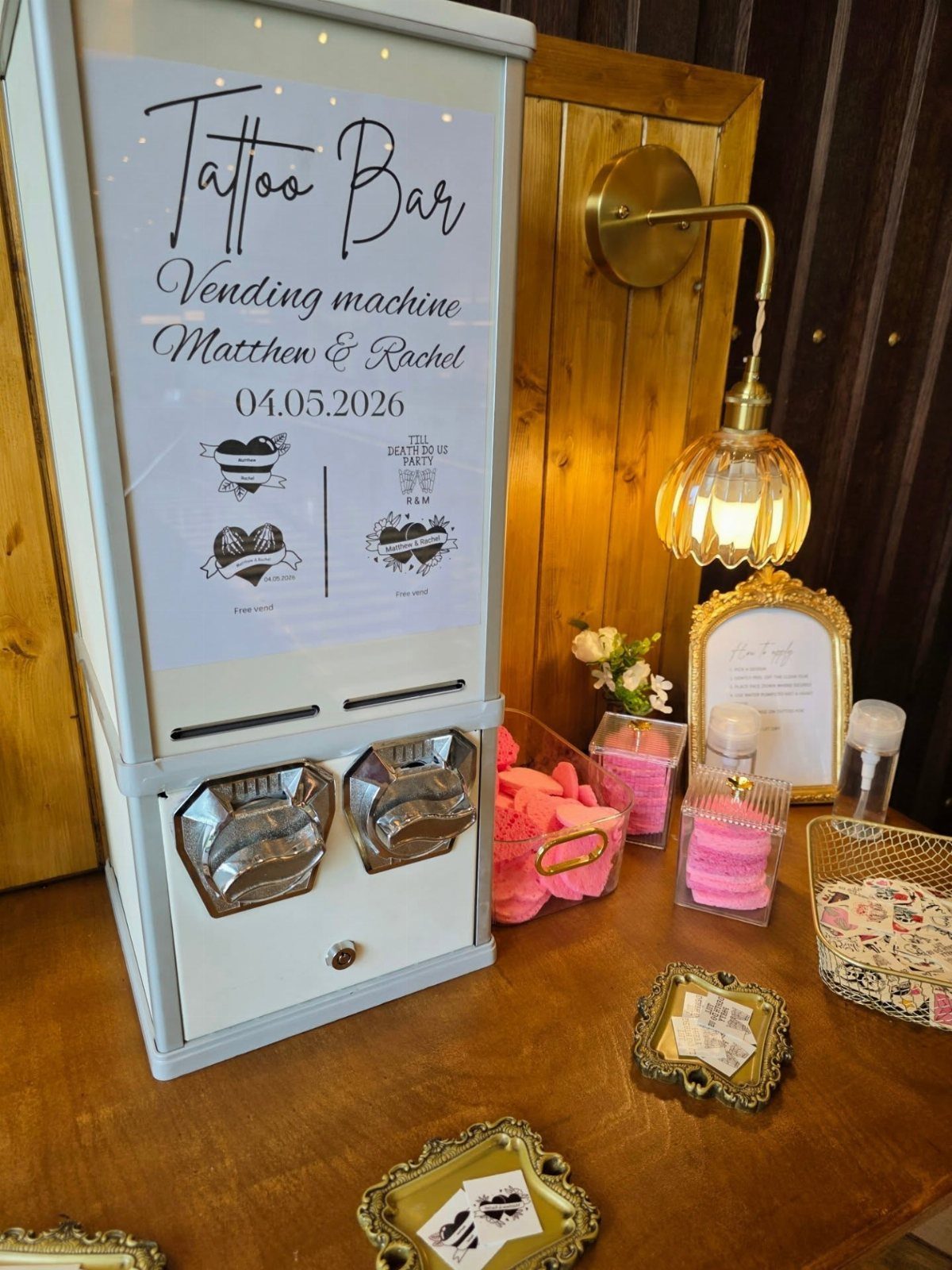 Tattoo bar vending machine with wedding signage and temporary tattoos on a table.