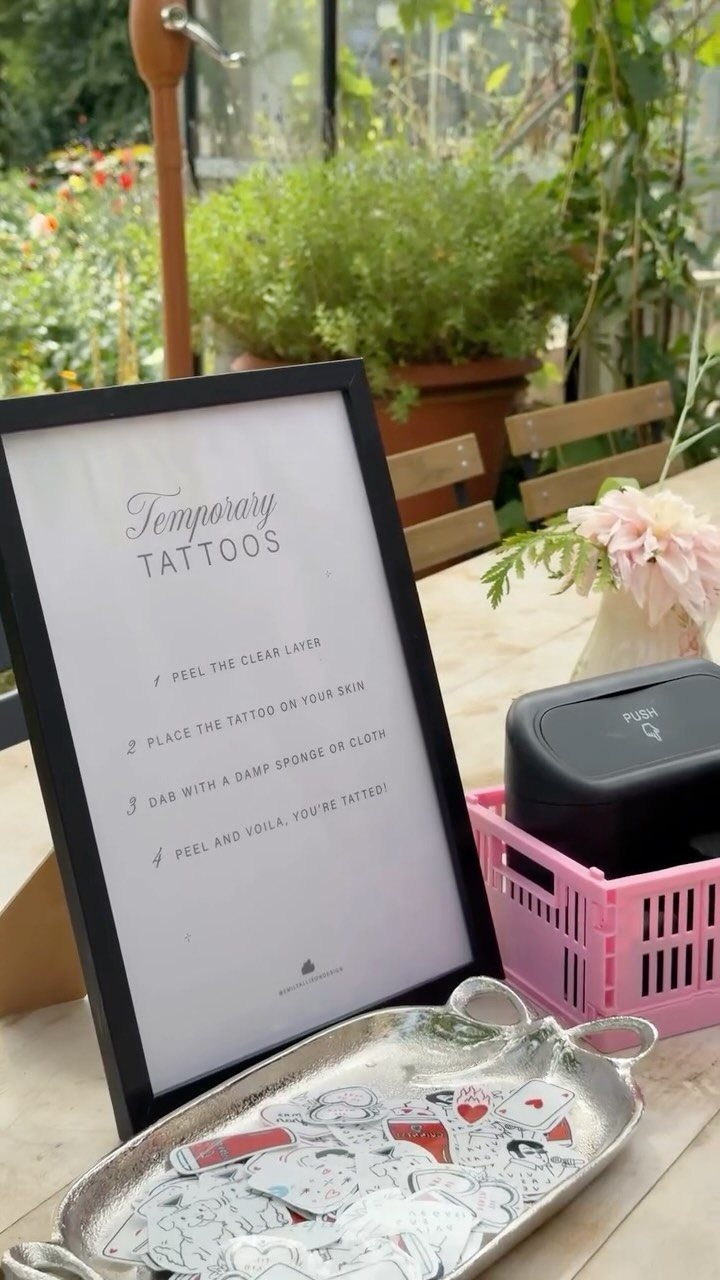 Framed temporary tattoo application instructions on a table with tattoo sheets and accessories.
