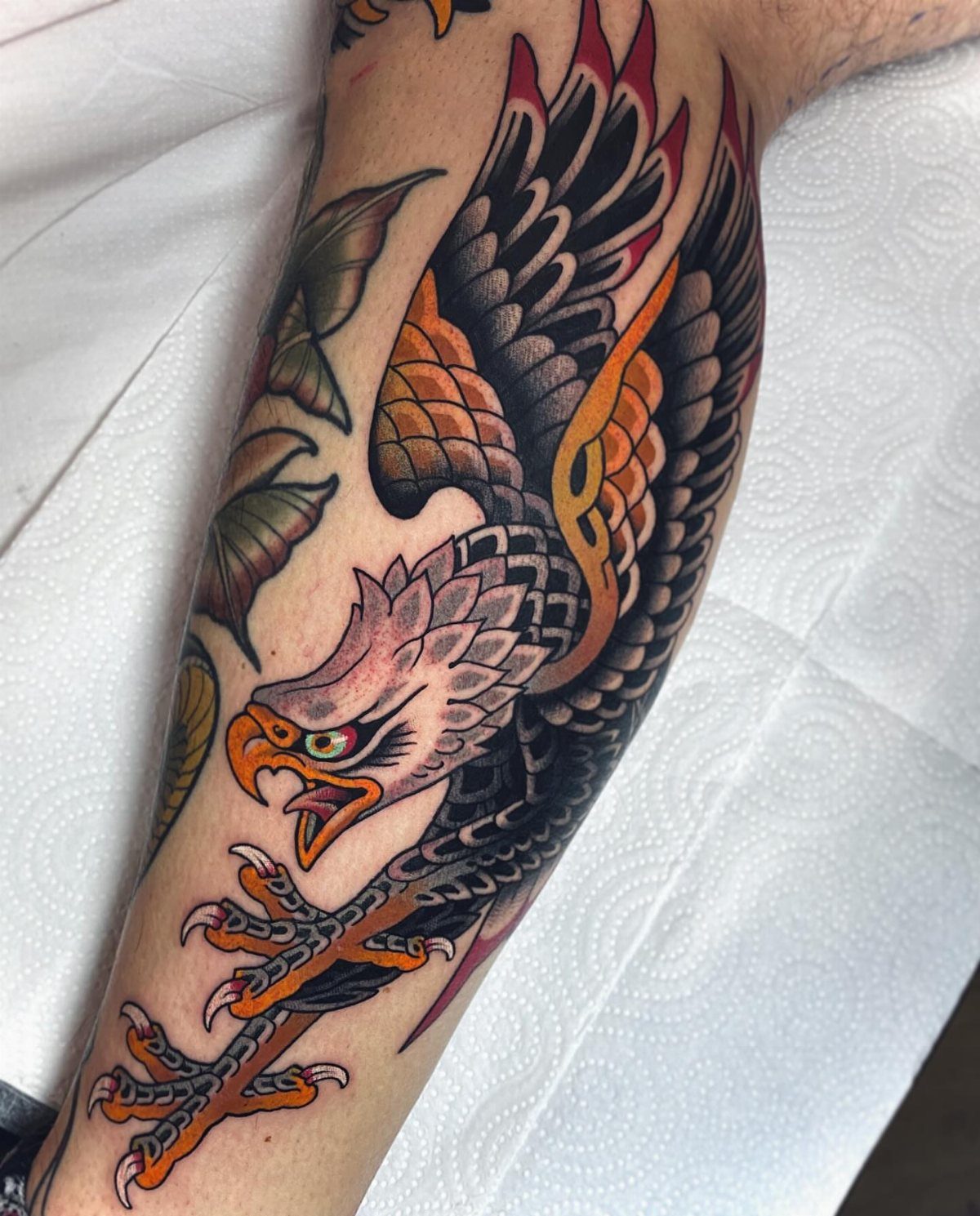 Traditional eagle tattoo with bold outlines and vibrant colors on a person's arm.