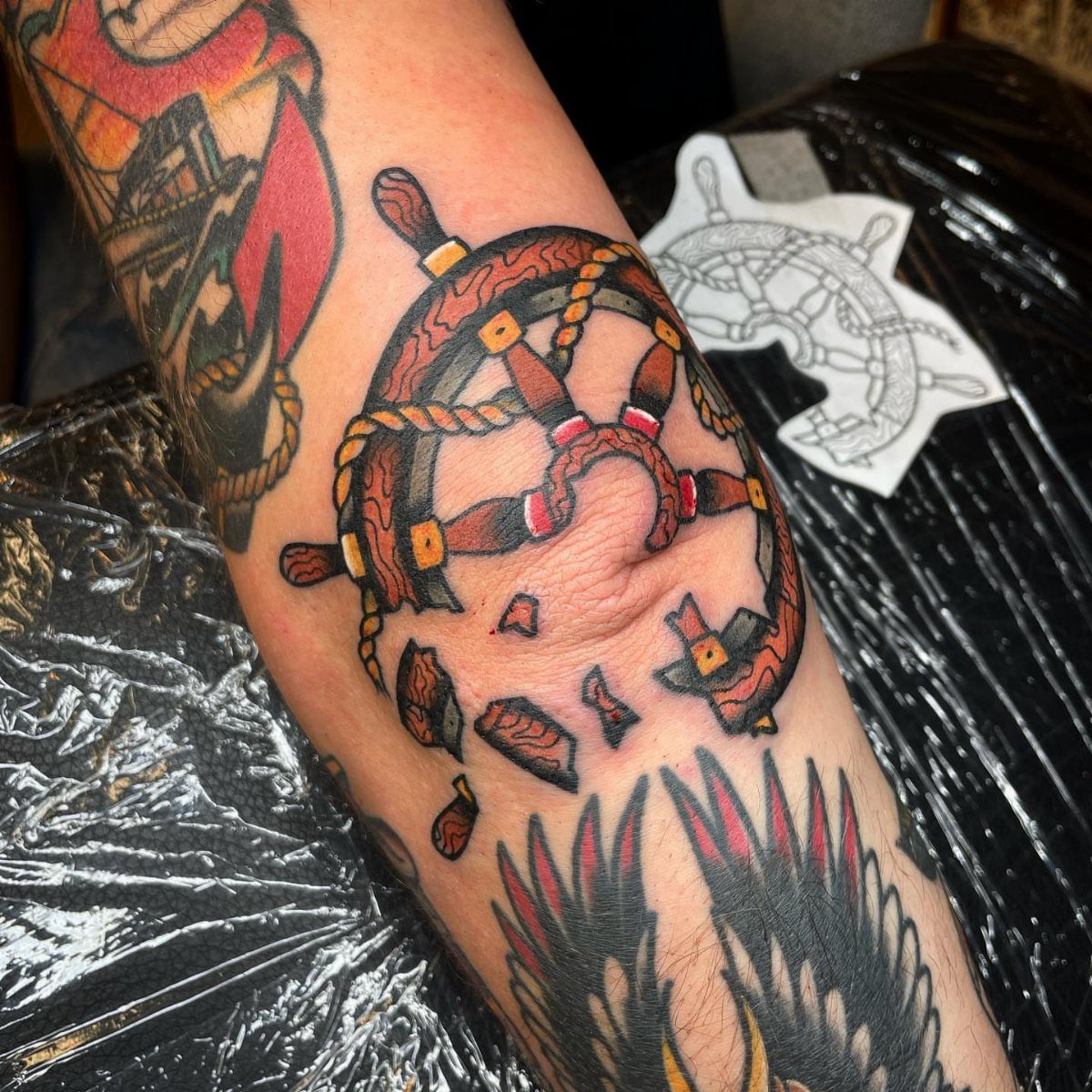 Broken ship's wheel tattoo on a leg in traditional American tattoo style